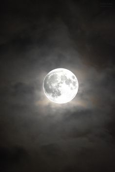 the full moon is shining brightly in the dark night sky with some clouds around it