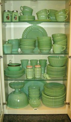 the shelves are filled with green dishes and plates