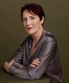 a woman with her arms crossed sitting at a table