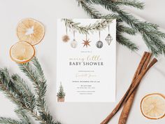 a baby shower with orange slices, cinnamon sticks and greenery next to it on a white surface