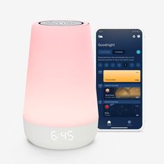 an alarm clock is next to a pink and white light - up speaker with the app on it