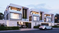 two cars are parked in front of a modern house at dusk with lights on the windows