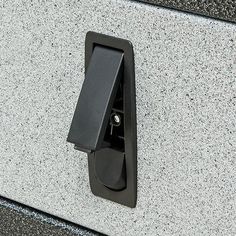 a close up of a door handle on a gray and black wall mounted device with an electrical outlet attached to it