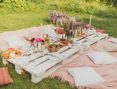 a picnic table set up with food and drinks on it in the middle of a field