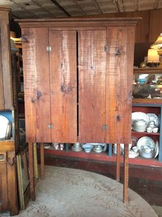 an old wooden cabinet with many plates on it in a room filled with other items