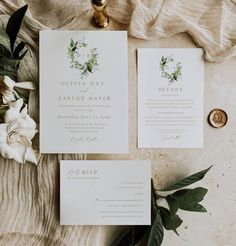 the wedding stationery is laid out on a table with flowers and greenery next to it