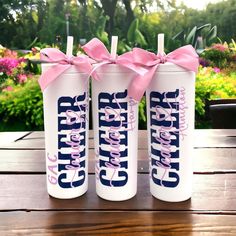 three personalized water bottles with pink bows on them are sitting on a wooden table