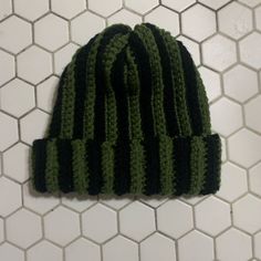 a green and black knitted hat sitting on top of a white tile floor