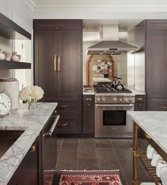 a kitchen with marble counter tops and stainless steel stove top oven, sink, and range hood