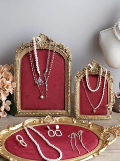 three gold frames with pearls and jewelry on them