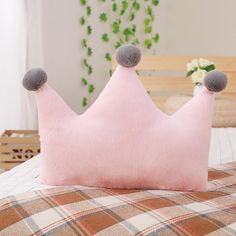 a pink pillow with two grey pom poms on it's sides sitting on a bed