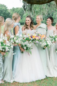 a group of women standing next to each other holding bouquets