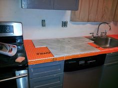 a kitchen with an orange counter top next to a sink and stove in it's corner