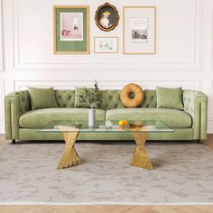 a living room with green couches and pictures on the wall above them, along with a coffee table