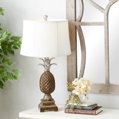 a pineapple lamp sitting on top of a white table next to a mirror and potted plant