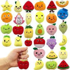 a hand holding an assortment of fruit and vegetables on strings with faces drawn on them