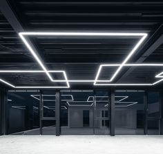 an empty room with several doors and lights on the ceiling is lit up by fluorescent lighting