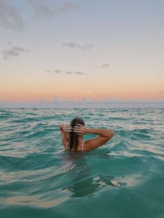 a woman floating in the ocean with her arms behind her head