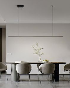 a dining room table with four chairs and a vase on the centerpiece in front of it