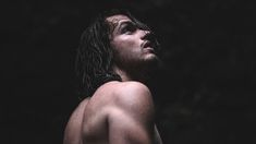 a shirtless man with wet hair and no shirt standing in front of dark background