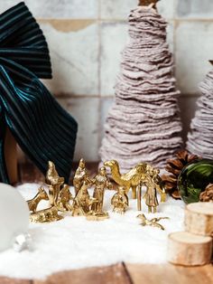 some gold figurines are sitting in the snow next to christmas trees and decorations