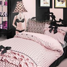 a black and white polka dot bed in a bedroom with pink walls, two framed pictures on the wall