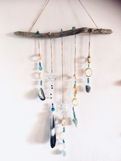 a wooden branch with beads hanging from it's sides next to a white wall