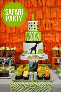 an assortment of cakes and cupcakes are displayed in front of orange streamers