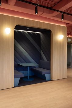 an empty room with blue benches and wooden partitions on the wall, in front of two lights