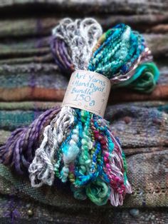 two skeins of yarn sitting on top of a pile of cloth covered in multicolored thread