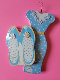 a cookie shaped like a pair of shoes hanging from a hook on a pink background