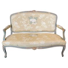 an old fashioned couch with floral fabric on the back and arms, sitting in front of a white background