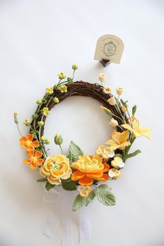 a wreath with yellow and orange flowers on it sitting on top of a white table