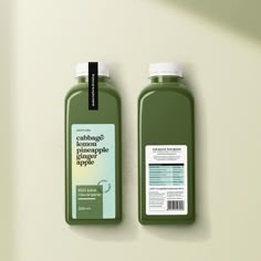 two bottles of green juice sitting on top of a counter next to each other,