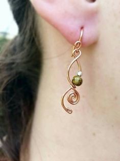 a close up of a person's ear wearing gold earrings with green beads on them