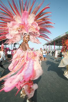 a woman in a pink feathered dress and headdress walking down the street