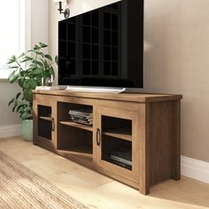 a flat screen tv sitting on top of a wooden entertainment center next to a window