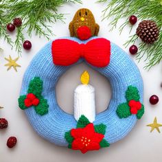 a knitted wreath with a lit candle surrounded by christmas decorations