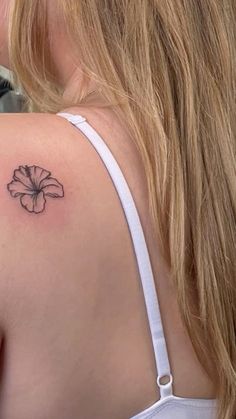 a woman with a small flower tattoo on her back shoulder and upper half of her arm