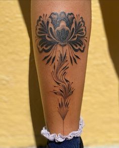 a woman's leg with a flower tattoo on the lower part of her leg