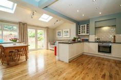 an open kitchen and dining room with skylights in the ceiling, hardwood flooring