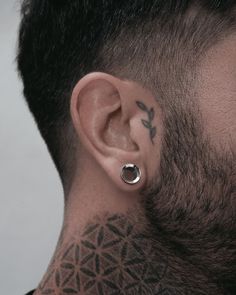 a man with tattoos on his neck and behind the ear is an ear piercing ring