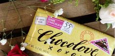 a chocolate bar sitting on top of a wooden table next to flowers and greenery