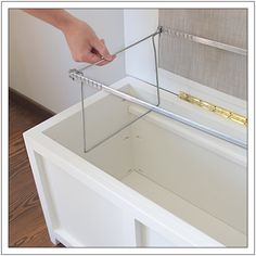 a person is opening the door to an empty drawer with a pair of tongs in it