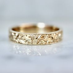 a gold wedding band with flowers on it