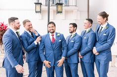 a group of men standing next to each other wearing blue suits and red tie ties