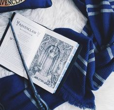 a harry potter book laying on top of a white blanket next to a blue scarf