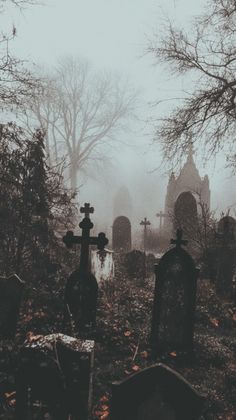 an old cemetery with tombstones and crosses in the fog