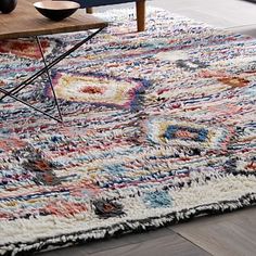 an area rug with various colors and shapes on the floor next to a coffee table