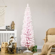 a pink christmas tree in the corner of a room next to a teddy bear and other toys